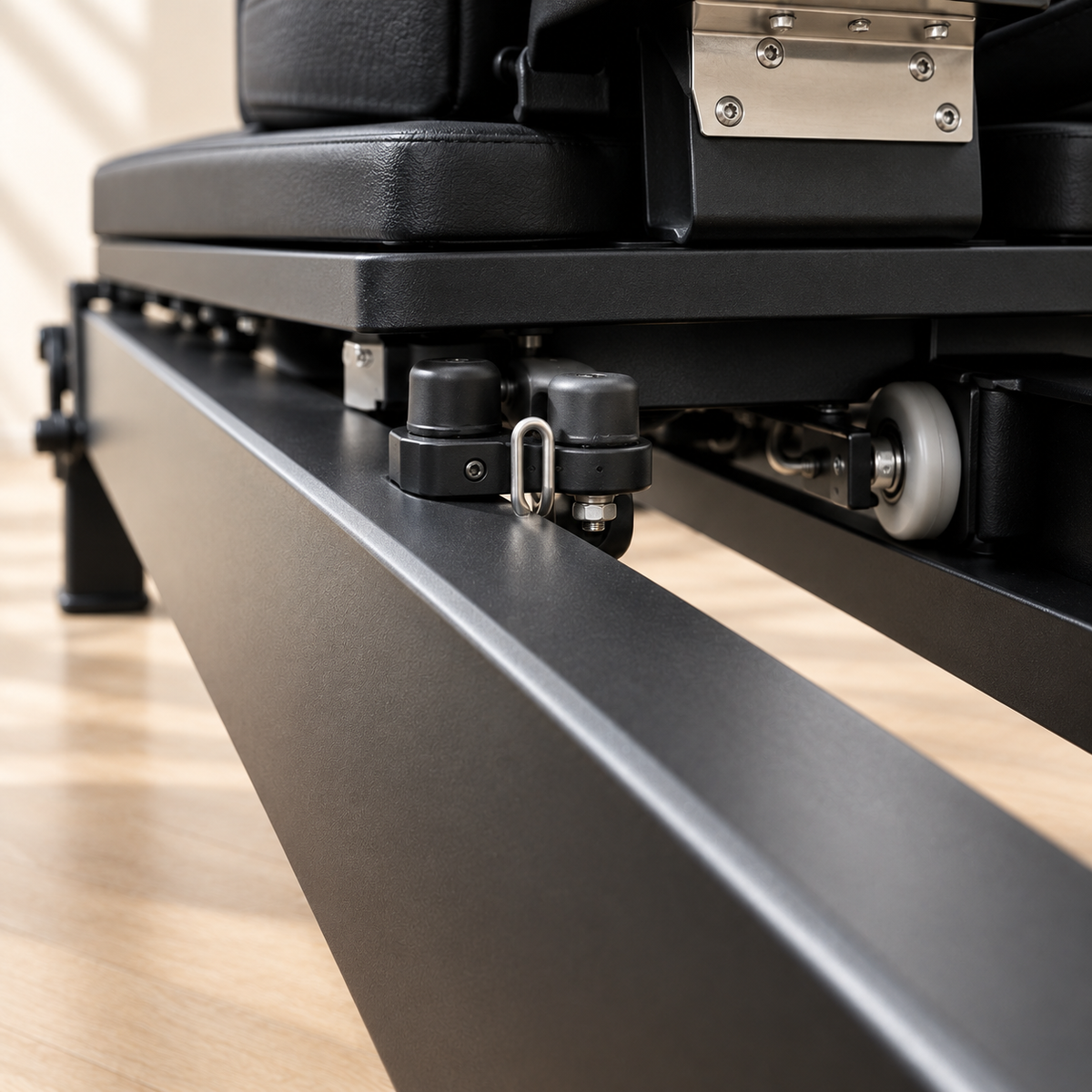 Détail du rail, des roulettes et du système de guidage du chariot du Pilates Reformer Astra en aluminium noir